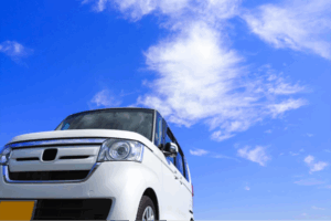 青空の下に停まる白い軽自動車。日本独自の軽自動車文化とコンパクトカーUXの象徴