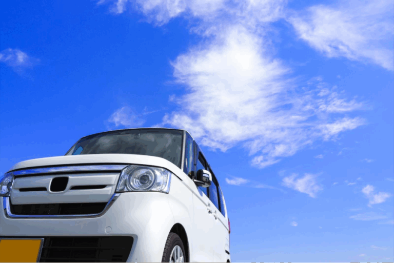 青空の下に停まる白い軽自動車。日本独自の軽自動車文化とコンパクトカーUXの象徴