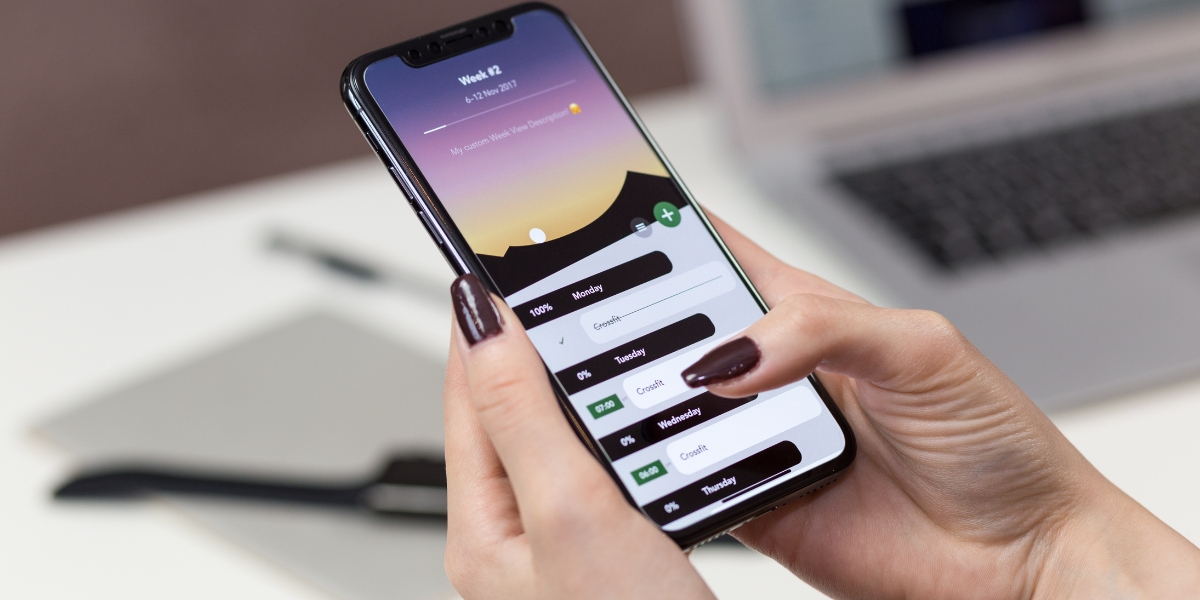 Person using a mobile health app to track weekly exercise schedule and wellness goals.