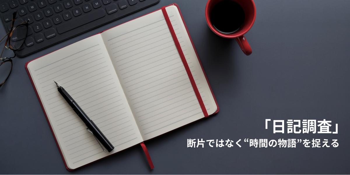 キーボードやコーヒーカップが置かれたデスクの上で開かれた、赤いノートとペン。ユーザーの日常の中で、体験が時系列の「物語」として記録されていく日記調査のコンセプトを象徴する画像。