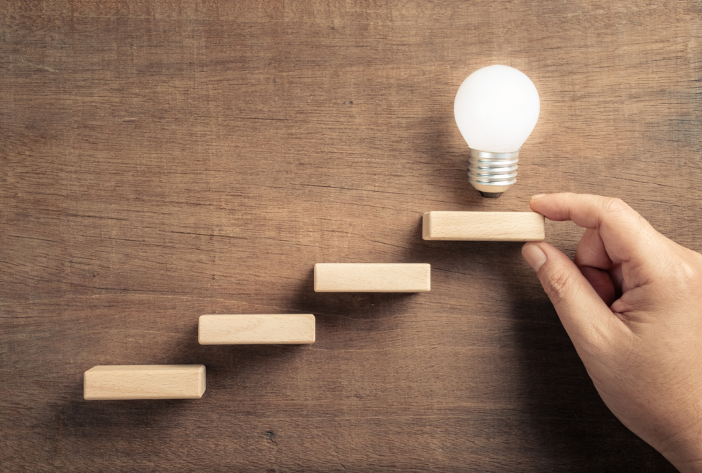 価値あるインサイト（電球）へ至る道筋を築くUXリサーチ。ユーザーの発言と行動のズレに隠された本音を発見する手法「コンテクスチュアルインクワイアリ」の4つの原則を、画像が示す4つのステップのように解説。この記事でユーザー行動の「なぜ？」を解明できます。