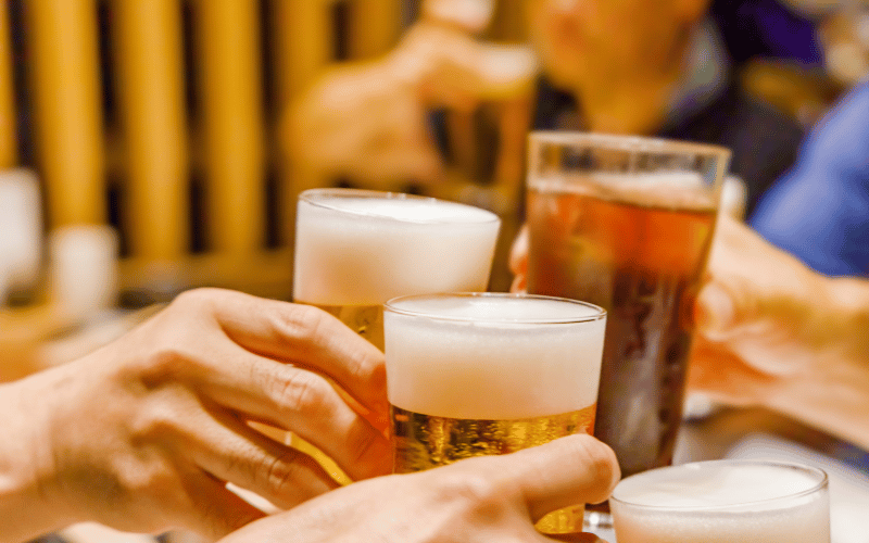  A close-up of several people toasting with glasses of beer, symbolizing the traditional alcohol-centric social gatherings that are becoming less central for Japan's Gen Z.