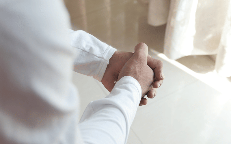 A person sitting with their hands clasped, conveying anxiety and emotional tension during a difficult conversation.